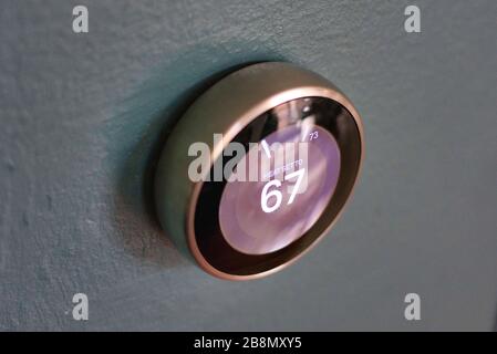 Termostato intelligente isolato su pareti blu chiaro dal basso. Nest intelligente tecnologia casa risparmio di denaro riscaldamento e raffreddamento. Bianco e nero Foto Stock