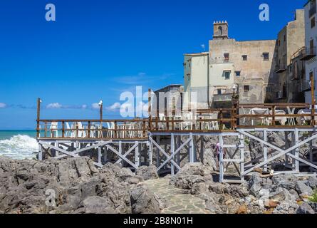 Molo in legno su sentiero su una costa rocciosa nella città di Cefalu, situato sulla costa tirrenica della Sicilia, Italia - vista con la Chiesa Santa Maria dell'Itria Foto Stock