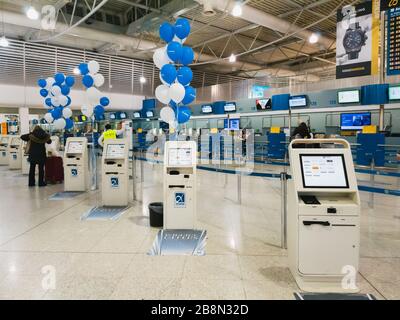 Atene, Grecia - Febbraio 11 2020: Un check-in self-service per la stampa della carta d'imbarco davanti ai banchi vuoti del check-in principale Foto Stock