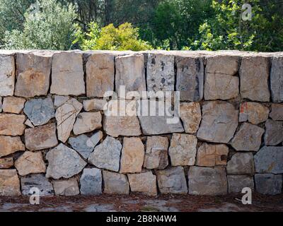 Muro di pietra di una fortezza fatto da rocce rotte. Un muro di pietra illuminato dal sole. Medievale, storico. Foto Stock