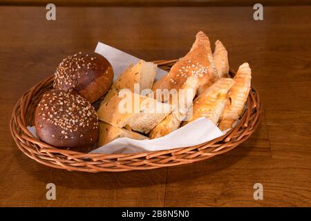 Pane rurale ai cereali naturale con spezie, erbe e semi di sesamo in un cesto di vimini. Apitizer utile prima di pranzo in un ristorante. Mediterraneo naturale Foto Stock