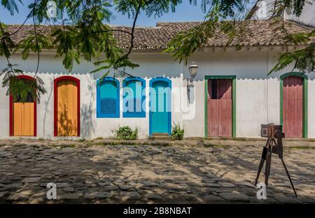 Facciata di tipica casa colorata con strada acciottolata e macchina fotografica vintage a Paraty, Rio de Janeiro, Brasile. Il centro coloniale preservato della città Foto Stock