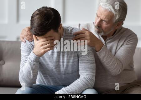 Il conforto del padre anziano che si prende cura del figlio adulto Foto Stock