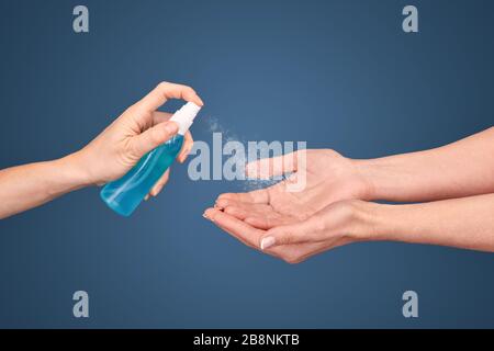 Donna di mezza età disinfetta le mani con spray Foto Stock