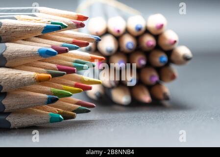 Un'immagine closeup di un mazzo di matite colorate su uno sfondo grigio con spazio per la copia Foto Stock