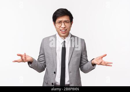 Perché cosa vuoi. Girovita-up ritratto di infastidito e frustrato giovane asiatico in abito grigio che è deluso e sconvolto con qualcuno che dice Foto Stock