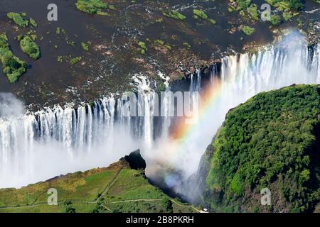 Vista aerea delle splendide Cascate Vittoria e del suo arcobaleno a causa della nebbia d'acqua nell'aria. Attrazioni turistiche in Zimbabwe e Zambia. Cascata enorme Foto Stock