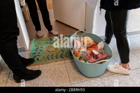 Friburgo, Germania. 20 Marzo 2020. I membri del personale del Malteser Hilfsdienst sono in piedi con il cibo di fronte ad una porta d'ingresso. Nel giro di tre giorni, il personale di Friburgo ha messo a punto un servizio di shopping e consegna per i bisognosi. Credit: Patrick Seeger/dpa/Alamy Live News Foto Stock