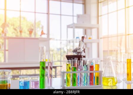 Reagente chimico in matracci per esperimenti scientifici di varie forme, dimensioni e con luce arancione. Foto Stock