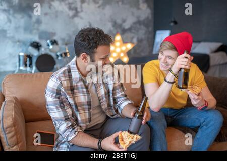 Due giovani che mangiano pizza e bevono birra Foto Stock
