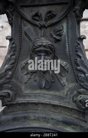Vienna, Austria. Statua in bronzo al mascarone parte della composizione della lanterna di strada di fronte al Burgtheater (Teatro della Corte Imperiale) Foto Stock