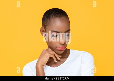 Donna African American sensazione triste e annoiato guardando verso il basso con mano sul mento isolato su sfondo giallo Foto Stock