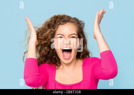 Scioccata arrabbiata giovane donna caucasica gridando isolato su sfondo blu chiaro studio Foto Stock