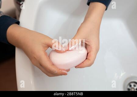 primo piano bambino che si insaponava le mani con sapone in bagno. Foto Stock