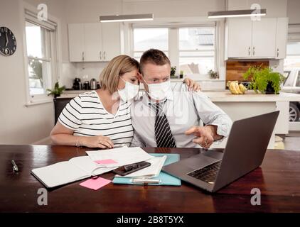 Recessione economica del coronavirus. Coppia stressata con maschere in auto-isolamento sopra le finanze domestiche e i debiti di piccola impresa durante la chiusura di quarantena. i Foto Stock