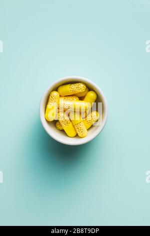 Capsule vitaminiche. Pillole di vitamina C in ciotola su sfondo colorato. Vista dall'alto. Foto Stock