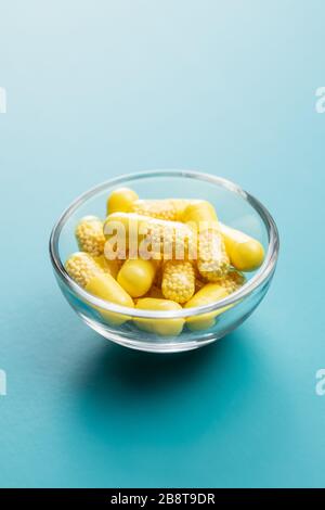 Capsule vitaminiche. Pillole di vitamina C in ciotola su sfondo blu. Foto Stock