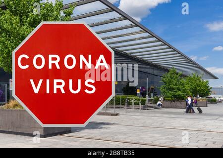 Immagine concettuale con grande cartello rosso di avvertenza Coronavirus di fronte al terminal di Heathrow, concetto di limitazioni di viaggio Foto Stock