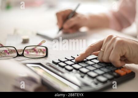 Concetto di calcolo della pensione, vecchie mani che contano le finanze su un calcolatore domestico, primo piano Foto Stock