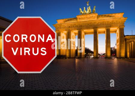 Berlino, Germania - 20 marzo 2020: Immagine concettuale con grande cartello rosso Coronavirus davanti alla porta di Brandeburgo al crepuscolo, limitazione di viaggio conc Foto Stock