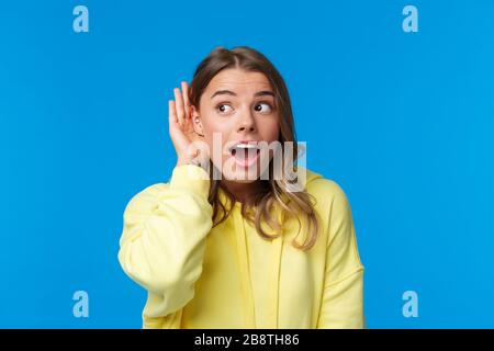 Ritratto ravvicinato e curioso di bionda giovane ragazza con orecchio trafitto, gossiping, eavesdropping e ascolto di qualcuno conversazione Foto Stock