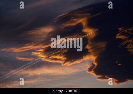 L'aereo commerciale vola in alto nel cielo in nuvole nere scure. Atmosfera cupa. Foto Stock