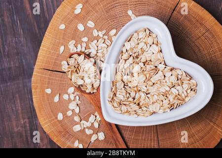 Farina d'avena in piastra a forma di cuore su superficie di legno Foto Stock