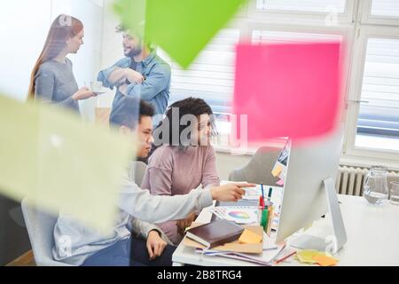 I Web designer e gli sviluppatori lavorano insieme su un PC nell'ufficio dell'agenzia Internet Foto Stock