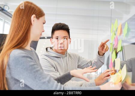 I giovani d'affari discutono le idee su appunti appiccicosi nel workshop di brainstorming Foto Stock