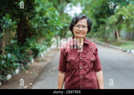 Primo piano nonna asiatica sicuro che porta occhiali stand nel parco Foto Stock