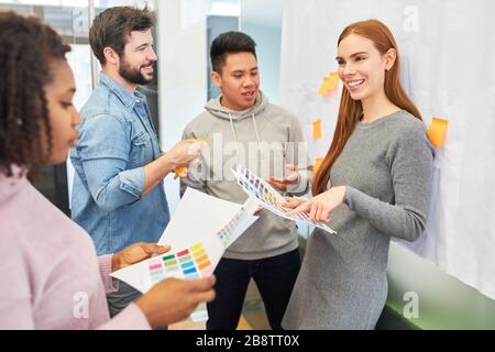 I grafici e gli sviluppatori discutono il disegno di colore di un Web site in una riunione Foto Stock