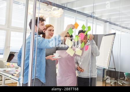 Studenti o giovani start-up nel workshop di brainstorming con note su una parete di vetro Foto Stock