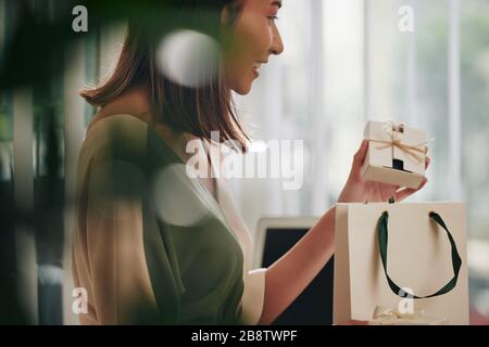 Felice giovane donna vietnamita che mette la scatola delle saponette nella confezione per il cliente Foto Stock