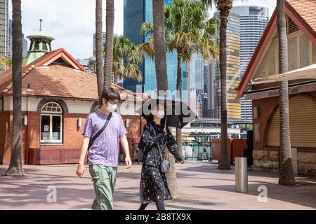 Centro di Sydney, Australia. Lunedì 23 Marzo 2020. Le coppie asiatiche indossano maschere facciali mentre camminano accanto a caffè chiusi a Circular Quay. Credit Martin Berry/Alamy Live News Foto Stock