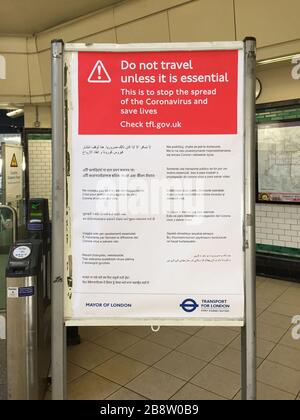 Morden, Londra, Regno Unito. 23 marzo 2020. Segno multilingue di viaggio essenziale durante la crisi di Covid-19 all'ingresso vuoto alla stazione metropolitana di Morden all'ora di punta di picco, il capolinea suburbano di Londra meridionale della Northern Line è normalmente imballato in questo momento. Credit: Malcolm Park/Alamy Live News. Foto Stock