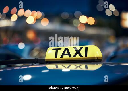Illuminazione cartello taxi sul tetto della macchina sulla strada della città di notte. Foto Stock