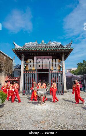 Donne locali in costumi tradizionali rossi camminando vicino al Tempio di Na Tcha. Macao, Cina. Foto Stock