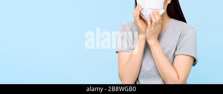 Giovane donna che indossa la maschera medica del viso tosse isolato su sfondo blu chiaro banner con spazio copia Foto Stock