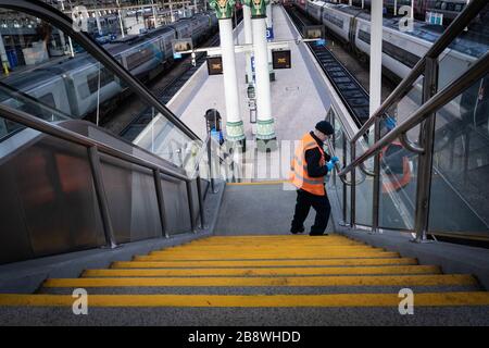 Manchester, Regno Unito. 23 marzo 2020. Manchester, Regno Unito 23 marzo 2020. Un pulitore indossa una maschera come precauzione contro la diffusione del coronavirus durante la pulizia della stazione ferroviaria. Credit: ÊAndy Barton/Alamy Live News Foto Stock