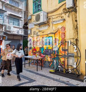 Turisti che camminano sulla stretta strada acciottolata nel centro storico. Macao, Cina. Foto Stock