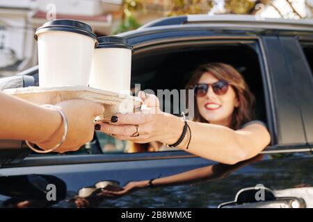 Cameriere che dà vassoio usa e getta con due tazze di caffè take out a una guida femminile piuttosto sorridente Foto Stock