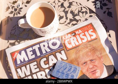 Primo piano di una tazza di tè su un vassoio per la colazione con la prima pagina del giornale della metropolitana che mostra il primo ministro Boris Johnson e Corona Virus titolo Foto Stock