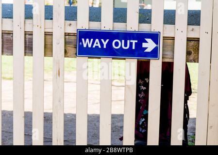 Uscita segno con freccia appesa su una recinzione Foto Stock