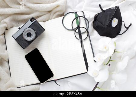 tempo di isolamento, malattia, fotocamera, notebook e maschera protettiva. soggiorno a casa. lavoro del fotografo durante la quarantena. quarantena e fotografia Foto Stock