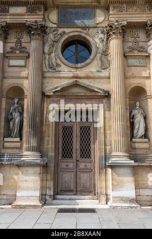 Antiquariato in legno intarsiato porta con pietra intagliata nella struttura di un antico palazzo a Parigi. Foto Stock