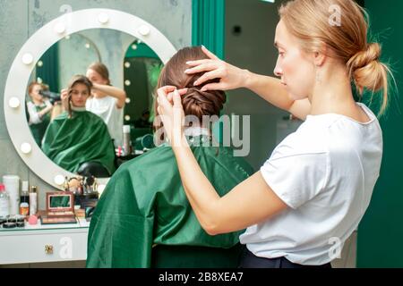 Il parrucchiere professionale fa l'acconciatura della donna nel salone di bellezza. Foto Stock