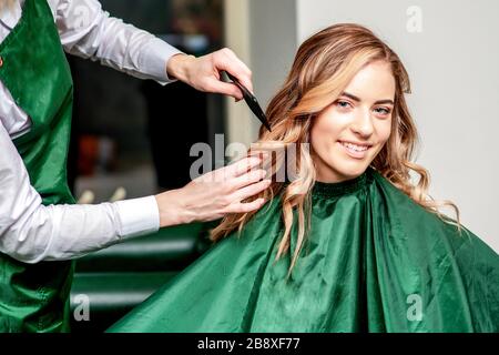 La ragazza riceve pettinare i suoi capelli dal parrucchiere nel salone. Foto Stock