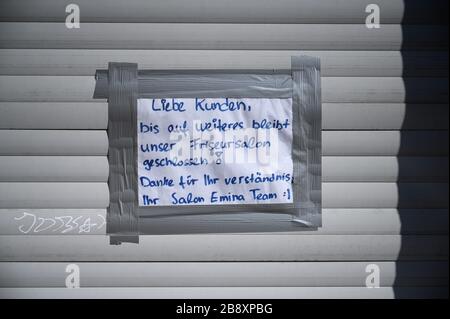 Stoccarda, Germania. 23 marzo 2020. Un foglietto di carta con l'iscrizione 'Cari clienti, fino a nuovo avviso il salone del nostro parrucchiere rimarrà chiuso' appende sulle persiane di un salone chiuso del parrucchiere. Per rallentare la diffusione del virus corona, i parrucchieri si sono chiusi. Credit: Sebastian Gollnow/dpa/Alamy Live News Foto Stock