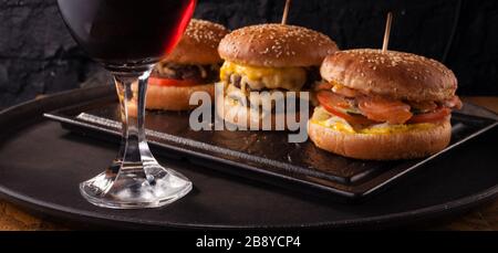 Birra fredda in un bicchiere e uno spuntino sotto forma di grandi hamburger succosi. Fast food. Foto Stock