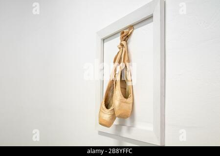 Sofia - 3 marzo 2020: Vecchie scarpe da ballerina appese in una cornice su una parete bianca, come ricordo della carriera di una ballerina Foto Stock